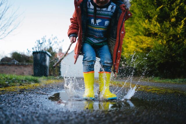 2026_04_Monthy-Market-Commentaries_Child-splashing-in-the-rain-with-rubber-rain-boots