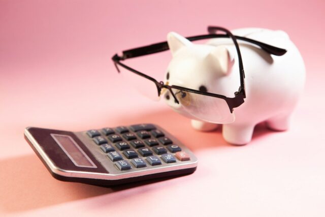 Retirement Calculators_A piggy bank wearing glasses next to a calculator.