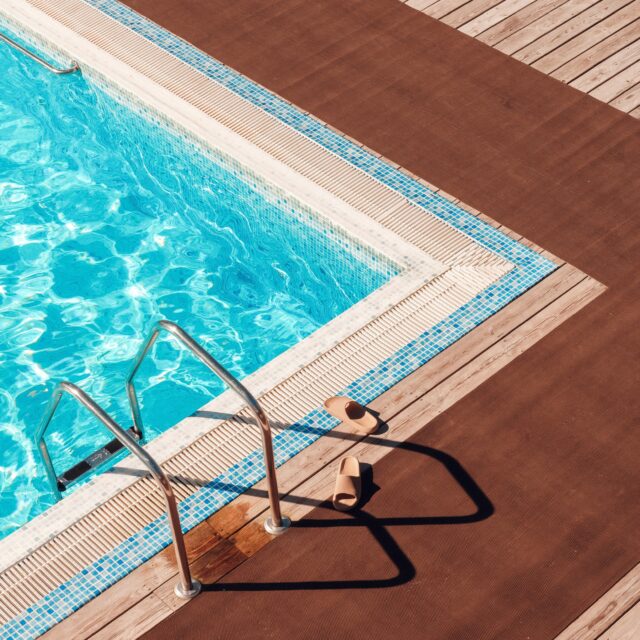 2026_07_July Market Commentary_Aqua Blue swimming pool with flipflops